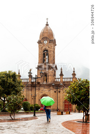Woman walking with an umbrella at the beautiful central square aof the small town of Nobsa in a rainy day 106944726