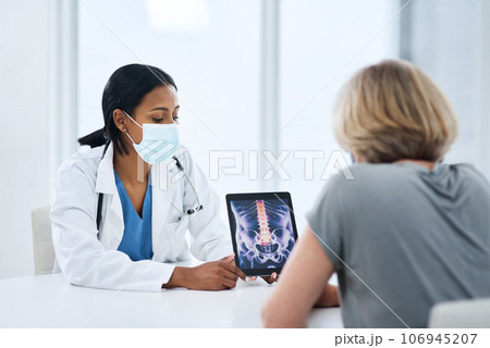 Doctor, patient and woman with tablet for spine, feedback or advice for injury, pain or safety with mask for covid. Medic, women and touchscreen for consulting, osteoporosis and explain with x ray 106945207