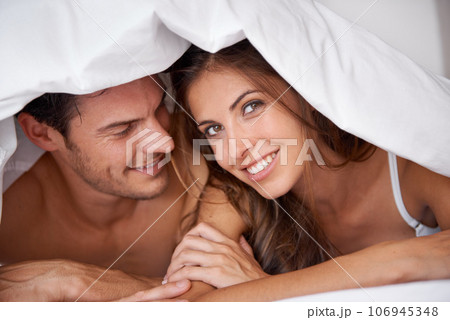 Portrait, couple and love in bed, waking up and bonding in bedroom together, flirting and romantic. Face, man and woman relax, intimate and resting at hotel for valentines day, anniversary or bond 106945348