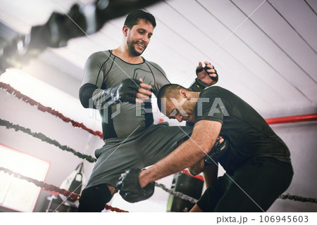 What a shot out of nowhere. Shot of two young male boxers facing each other in a training sparing match inside of a boxing ring at a gym during the day. 106945603