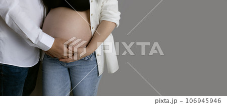 unrecognizable people pregnant body of woman and man in casual support mom's belly on gray background 106945946