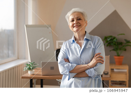 Portrait of confident stylish european middle aged senior woman at workplace. Stylish older mature 60s gray haired lady businesswoman in modern office. Boss leader teacher professional worker 106945947