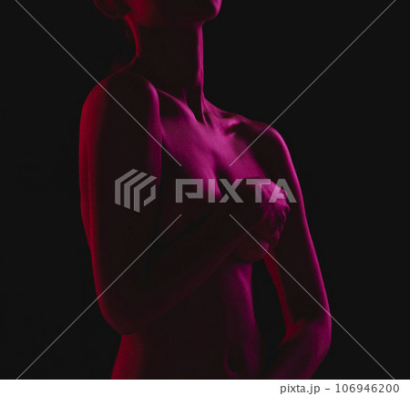 Nude, sexy and naked woman body covering boobs feeling sensual isolated in a dark studio background for sexual desire. Seduction, art and skin by erotic female model with hands on breasts or chest 106946200
