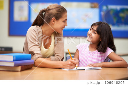 School, education or learning with a girl student and teacher in a classroom together for writing or child development. Study, scholarship and teaching with a woman educator helping a child in class 106946205