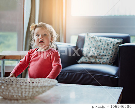 Children, baby and a girl in the living room of her home with mockup or flare looking curious while standing alone. Kids, development and lifestyle with a cute female child in a house during the day 106946386