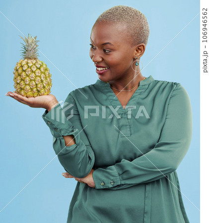 Smile, pineapple for health or nutrition and a black woman in studio on a blue background for diet. Wellness, fruit or food with a happy young person looking confident for healthy eating or detox Smile, pineapple for health or nutrition and a black woman in studio on a blue background for diet. Wellness, fruit or food with a happy young person looking confident for healthy eating or detox 106946562
