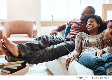 Couple, relax and watching tv on a sofa, happy and smile while bonding in their home together. Television, resting and black woman with man on a sofa, resting and having fun in the living room 106946702