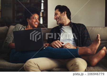 Laptop, relax and an interracial couple streaming a movie using an online subscription service for entertainment. Computer, watching or internet with a man and woman bonding together over a video 106946779