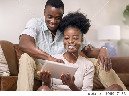 Would you look at this. Shot of a young couple using a digital tablet together at home. Would you look at this. Shot of a young couple using a digital tablet together at home. 106947128