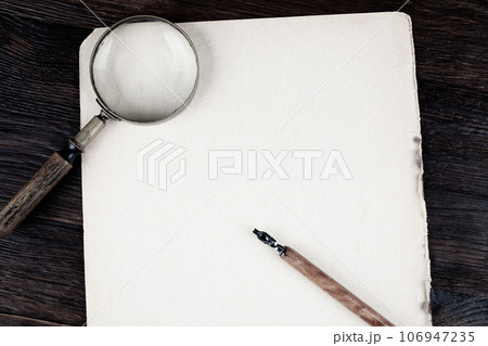 Magnifying glass with old paper and ink feather pen 106947235