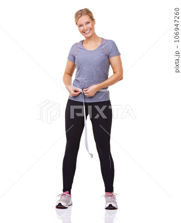 Pleased with her progress. Studio shot of an attractive young woman measuring her workout progress with a tape measure. 106947260