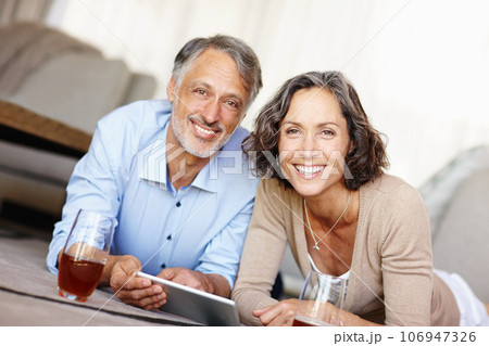 Spontaneity is the spice of life. Portrait of a happy mature couple lying on the floor and using a digital tablet. 106947326
