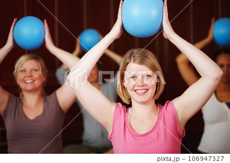 Pilates, fitness and training of a happy woman in a health and wellness class in a yoga studio. Ball workout and exercise of a relax female from Germany with a smile trying to be healthy at a gym 106947327