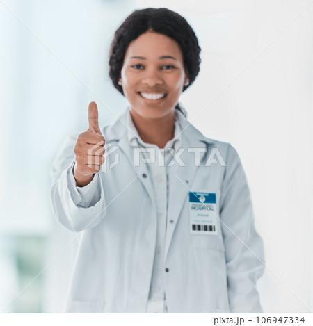 Some heroes wear white coats. Portrait of a young doctor showing thumbs up in a hospital. Some heroes wear white coats. Portrait of a young doctor showing thumbs up in a hospital. 106947334