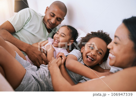 Happy family, relax and playing in bed with smile for free time, weekend or fun holiday morning at home. Mother, father and children relaxing and laughing together for playful joy in the bedroom 106947339