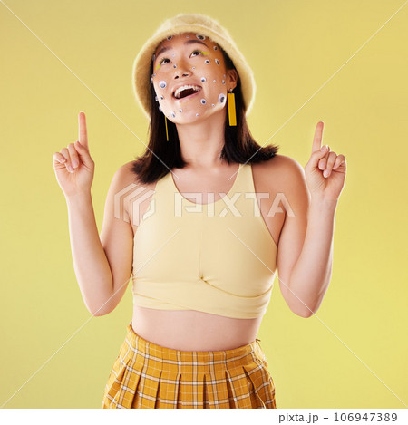 Thinking, pointing and woman with eyes for comedy isolated on a yellow background in a studio. Idea, comic and Asian girl with a gesture up and facial product for expression and funny on a backdrop Thinking, pointing and woman with eyes for comedy isolated on a yellow background in a studio. Idea, comic and Asian girl with a gesture up and facial product for expression and funny on a backdrop 106947389