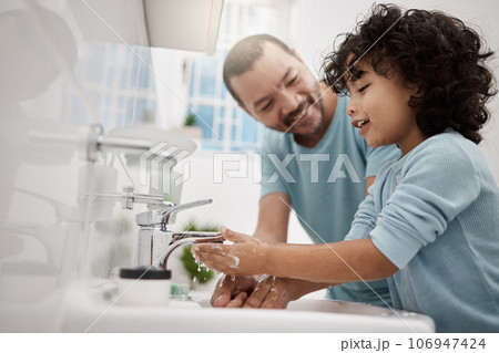 Now youll feel extra fresh. Shot of a father helping his son wash his hands and face at a tap in a bathroom at home. 106947424