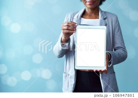 Blank screen and copy space on a tablet screen for digital marketing and advertising. Closeup of female hands showing mobile device. A woman presenting technology and website against blue background Blank screen and copy space on a tablet screen for digital marketing and advertising. Closeup of female hands showing mobile device. A woman presenting technology and website against blue background 106947801