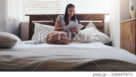 Notebook, writing and woman in bed with a diary for idea, memory or personal entry in her home. Book, journal and female person with notes for brainstorming, idea and creative life goal in a bedroom 106947973