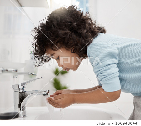 Staying clean and fresh. Shot of an adorable little boy washing his hands and mouth at a tap in a bathroom at home. 106948044