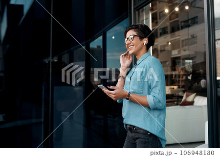 I love this song. Cropped shot of an attractive woman standing outside and putting her earpods in to listen to music through her cellphone. 106948180