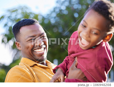 Lots of tickles, even more laughter. an adorable little boy sharing a playful moment with his father in a garden. 106948208