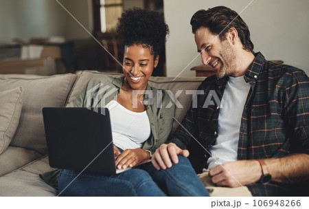 Were updating all our blogs today. Shot of a happy young couple using a laptop while relaxing on a couch in their living room at home. 106948266
