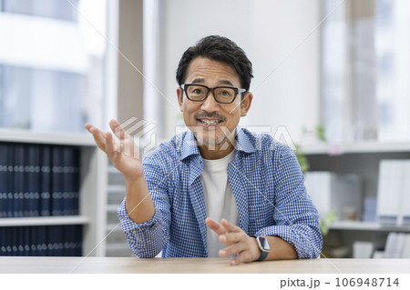 カメラ目線で話すメガネをかけた50代の男性　 106948714