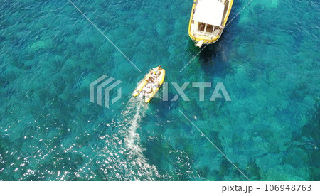 People on boat from above, sailing in Greece and summer sun on ocean holiday, relax in freedom and nature. Yacht vacation, aerial view of travel and tropical cruise on sea adventure to Greek island. 106948763