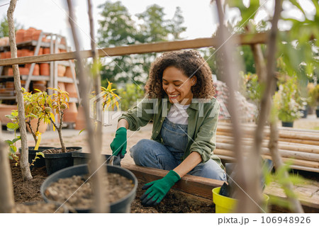 Professional woman garden worker transplants plants and takes care of flowerpots in botanic shop Professional woman garden worker transplants plants and takes care of flowerpots in botanic shop 106948926