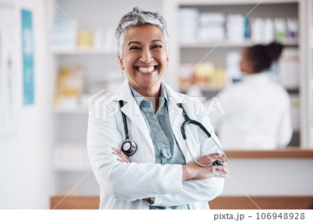 Mature, pharmacist or portrait of happy woman with arms crossed in healthcare clinic or drugstore. Proud, wellness or confident female doctor by pharmacy medication or medicine on shelf ready to help Mature, pharmacist or portrait of happy woman with arms crossed in healthcare clinic or drugstore. Proud, wellness or confident female doctor by pharmacy medication or medicine on shelf ready to help 106948928