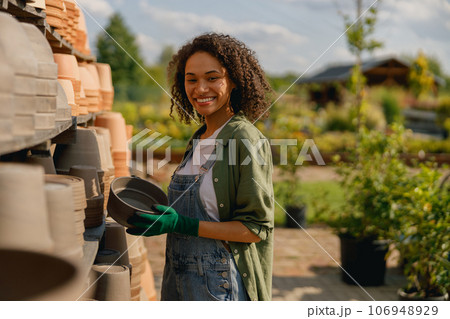 Woman gardener standing near shelves full of empty flowers pots in garden center 106948929