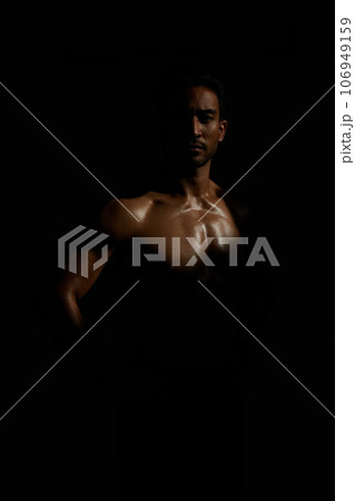 Topless, muscle and portrait man in dark background for fitness inspiration, beauty aesthetic or strong body. Shadow aesthetic, topless male model or body builder in creative studio with art lighting Topless, muscle and portrait man in dark background for fitness inspiration, beauty aesthetic or strong body. Shadow aesthetic, topless male model or body builder in creative studio with art lighting 106949159