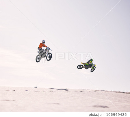 Dune, jump and men on motorbike together for practice, training and extreme sports energy in nature. Professional dirt biking challenge, friends and danger with motorcycle competition on desert hill. Dune, jump and men on motorbike together for practice, training and extreme sports energy in nature. Professional dirt biking challenge, friends and danger with motorcycle competition on desert hill. 106949426