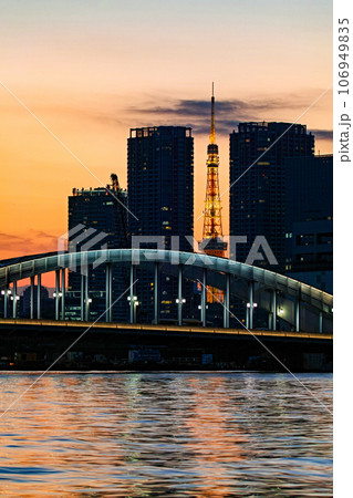 東京都/ 勝鬨橋とビルの隙間の東京タワー越しに見える夕陽（夕景） 106949835