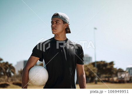 Soccer, sports and training with a man athlete holding a ball on a grass pitch or field before a game. Fitness, football and exercise with a male player thinking about a match outside during summer 106949951