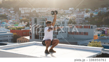 Man, fitness and squat with dumbbell on rooftop in workout, training or outdoor exercise in city. Active male person, athlete or bodybuilder lifting weights on balcony for healthy body or wellness 106950761