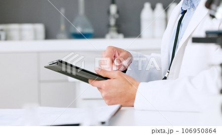 Laboratory scientist typing on a digital tablet and examining a dna test reaction to monkeypox virus during medical research. Biochemical engineer searching for a breakthrough cure on technology 106950864