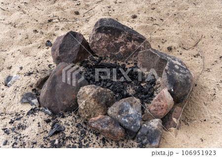 an extinct bonfire of stones on the beach. An extinct campfire. an extinct bonfire of stones on the beach. An extinct campfire. 106951923