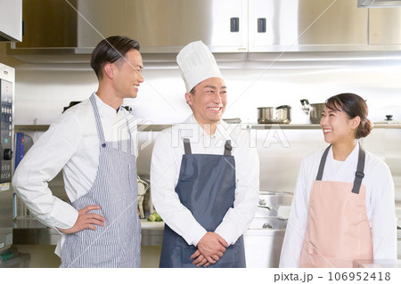 笑顔で会話をする厨房の調理スタッフたち 笑顔で会話をする厨房の調理スタッフたち 106952418
