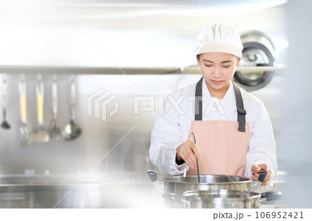 厨房で料理を作る白衣姿の若い女性 厨房で料理を作る白衣姿の若い女性 106952421