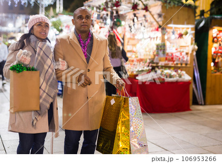 Happy married couple with packages of gifts at new year fair Happy married couple with packages of gifts at new year fair 106953266