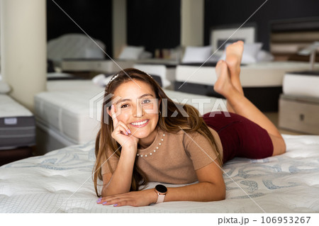 Pretty woman testing softness of new mattress Pretty woman testing softness of new mattress 106953267