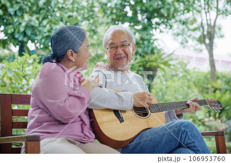 Happy Asian senior couple elderly man playing guitar while his wife singing together outdoors at home, Activity family health care, Enjoying lifestyle during retirement life having fun of senior older Happy Asian senior couple elderly man playing guitar while his wife singing together outdoors at home, Activity family health care, Enjoying lifestyle during retirement life having fun of senior older 106953760