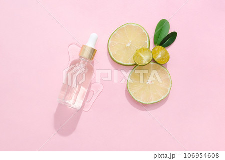 Lemon and kumquat are natural ingredients rich in vitamin C. Minimalist scene for advertising. Blank space on dropper bottle for design. Fresh slices of lime and kumquat are decorated 106954608