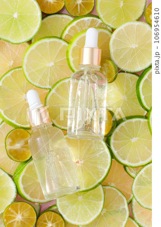 Top view of two unlabeled serum bottles placed on top of line and kumquat slices. Creative scenes for product advertising. Dropper bottles without label for design 106954610