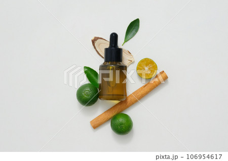 Scene for advertising essential oil products or scent solutions. Dropper bottle containing essential oils decorated with lemon, kumquat and cinnamon on a white background. 106954617