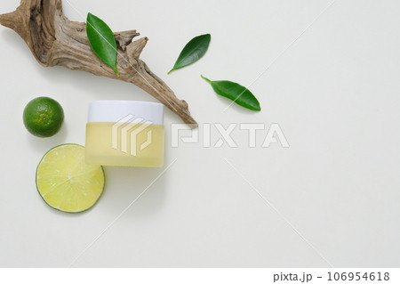 A yellow cosmetic jar decorated on white background with kumquat, lime and dry branch. Minimalist concept for advertising and branding product. Copy space 106954618