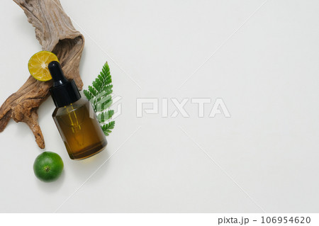 On a white background, an amber bottle displayed with kumquat slices. Space for cosmetic product mockup. Product and promotion concept for advertising. Natural ingredient rich in vitamin C 106954620