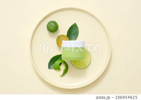 Minimalist concept for advertising cosmetic with natural ingredient rich in vitamin C. A green cream jar unlabeled mockup for design, decorated with kumquats on beige background 106954625